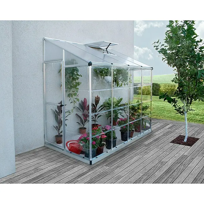 Palram – Canopia Invernadero Lean To - Medidas ext. (An x Pr): 123,8 x 243,8 cm, Material de la pared lateral: Plástico, 0,7 mm, Plateado - Un invernadero con plantas en una terraza de madera, ideal para el jardín o como ampliación de la casa.