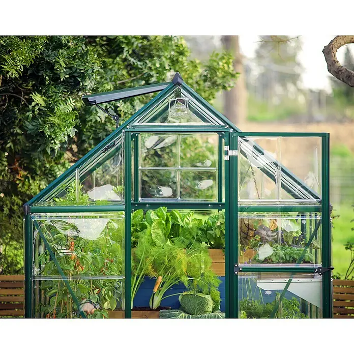 Palram – Canopia Invernadero Hybrid - Medidas ext. (An x Pr): 185 x 306 cm, 0,7 mm, Verde - La imagen muestra un invernadero verde con la puerta abierta, lleno de diversas verduras, bajo una exuberante vegetación.