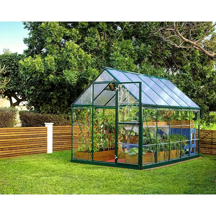 Palram – Canopia Invernadero Hybrid - Medidas ext. (An x Pr): 185 x 306 cm, 0,7 mm, Verde - Invernadero lleno de plantas en un jardín verde con césped y una valla de madera al fondo.