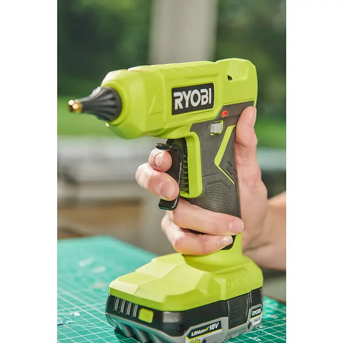Ryobi ONE+ Akku-Heißklebepistole RGLU18-0 - 18 V, Ohne Akku, Durchmesser Klebepatrone: 11 mm - 12 mm - Eine kabellose Ryobi-Heißklebepistole in Grün und Schwarz wird von einer Hand gehalten, bereit für Bastel- und Reparaturarbeiten.