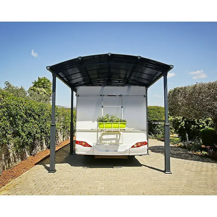 Palram – Canopia Carport Alpine - Medidas ext. (An x Pr): 3,59 x 4,35 m, Carport individual, Antracita - Una caravana blanca está estacionada bajo una cochera negra, con una jardinera verde en la parte trasera.