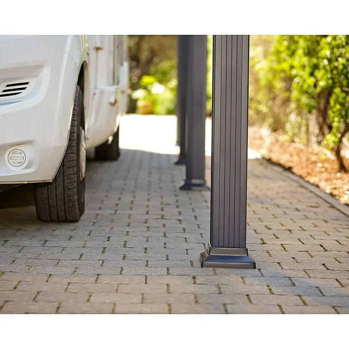 Palram – Canopia Carport Alpine - Medidas ext. (An x Pr): 3,59 x 12,9 m, Carport individual, Antracita - Imagen de una cochera con robustas columnas grises, que proporciona una plaza de aparcamiento para una autocaravana blanca. El suelo está pavimentado.