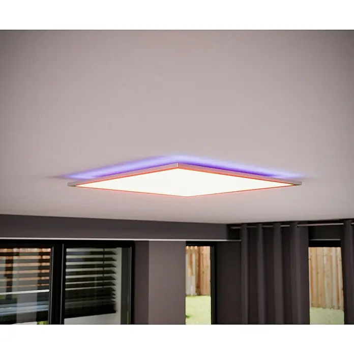 Tween Light LED-Panel RGB-RC-CCT-DIM32,5 W, L x B x H: 59,5 x 59,5 x 5,5 cm, Weiß, RGBW - Deckenleuchte mit quadratischer LED-Platte, die ein warmes Licht abgibt, umgeben von einem violetten Farbton, hängt in einem modernen Raum.