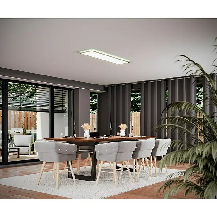 Tween Light LED-Panel RC-CCT-DIM-RGB-Backlight - 36 W, L x B x H: 120 x 30 x 5 cm, Weiß, RGBW - Das Bild zeigt einen Esstisch mit grauen Stühlen, der auf einem hellen Teppich steht. Über dem Tisch hängt eine moderne, rechteckige Deckenleuchte.