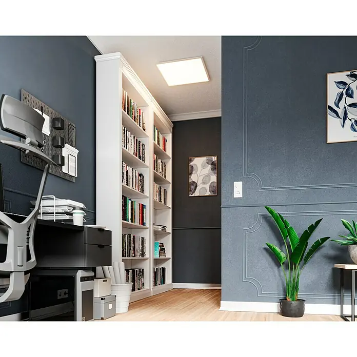 Tween Light LED-Panel RC-CCT-DIM - 36 W, L x B x H: 60 x 60 x 5 cm, Weiß, Mehrfarbig - Ein beleuchtetes quadratisches Paneel leuchtet über einem Homeoffice mit einem großen weißen Bücherregal und einem eleganten Schreibtisch.