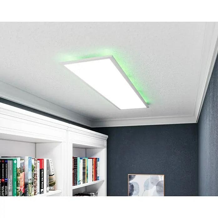 Tween Light LED-Panel RC-CCT-DIM-RGB-Backlight - 36 W, L x B x H: 120 x 30 x 5 cm, Weiß, RGBW - Ein rechteckiges LED-Deckenpanel mit grüner Hintergrundbeleuchtung, montiert in einer modernen Inneneinrichtung mit Bücherregal.