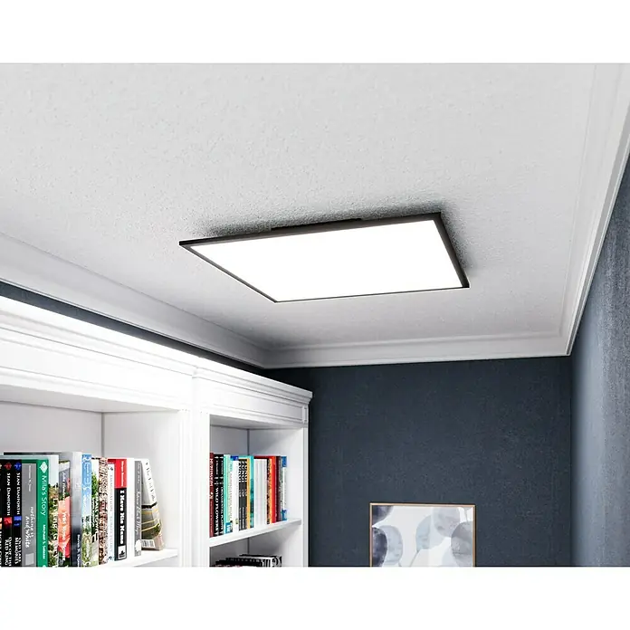 Tween Light LED-Panel CCT-RC-DIM32,5 W, L x B x H: 60 x 60 x 5 cm - Eine moderne, flache LED-Deckenleuchte mit schwarzem Rahmen, die in einem stilvollen Raum mit Bücherregal und Wandkunst hängt.