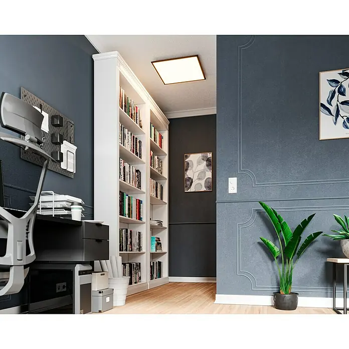 Tween Light LED-Panel CCT-RC-DIM32,5 W, L x B x H: 60 x 60 x 5 cm - Bürogestaltung mit einem weißen Bücherregal, das mit Büchern gefüllt ist, unter einer quadratischen Deckenleuchte. Der Raum hat auch eine moderne Dekoration.