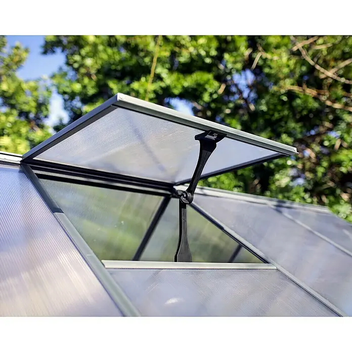 Palram – Canopia Invernadero Hybrid - Medidas ext. (An x Pr): 185 x 126 cm, 0,7 mm, Antracita - Primer plano de una ventana de invernadero con apertura automática, con árboles al fondo.