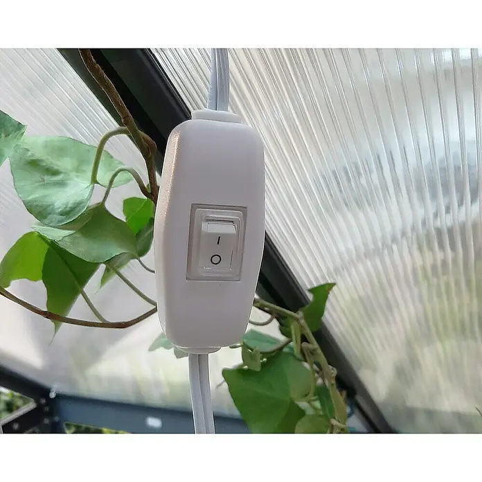 Palram – Canopia Plafón Brighton - Largo: 55 cm - Primer plano de un interruptor blanco con cable, rodeado de hojas verdes, sobre un fondo transparente.