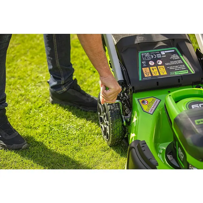 Greenworks 60V Akkusystem Akku-Rasenmäher GD60LM46SP - 60 V, 1 Akku, 4 Ah, Schnittbreite: 46 cm - Detailansicht eines Greenworks Pro Akku-Rasenmähers mit Bedienelementen und Hinweisschildern, umgeben von Gras.