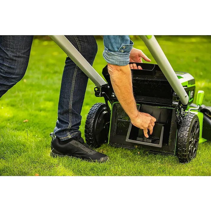 Greenworks 60V Akkusystem Akku-Rasenmäher GD60LM46SP - 60 V, Ohne Akku, Schnittbreite: 46 cm - Eine Person leert den Fangkorb eines grünen Rasenmähers auf einer Rasenfläche. Der Rasenmäher ist gut sichtbar.