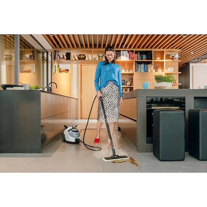 Kärcher Dampfreiniger SC 5 EasyFix Iron - 2.250 W, Aufheizzeit: 3 min, Behältervolumen: 1,5 l - Eine Frau benutzt einen Kärcher Dampfreiniger zur Reinigung eines Küchenbodens. Das Gerät steht hinter ihr auf dem Boden.