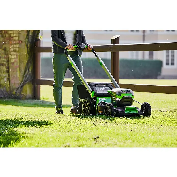 Greenworks 60V Akkusystem Akku-Rasenmäher GD60LM51SP - 60 V, 1 Akku, 4 Ah, Schnittbreite: 51 cm - Ein grüner Rasenmäher von Greenworks in Aktion, bedient von einer Person auf einem gepflegten Rasen.