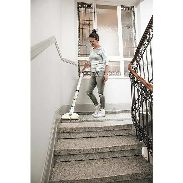 Kärcher Akku-Wischmopp EWM 2 - 7,4 V, Akkulaufzeit: 20 min, Flächenleistung: 180 m²/h - Frau reinigt Treppe mit Kärcher Hartbodenreiniger FC 7. Das Gerät entfernt mühelos Staub und Flüssigkeiten in einem Schritt.