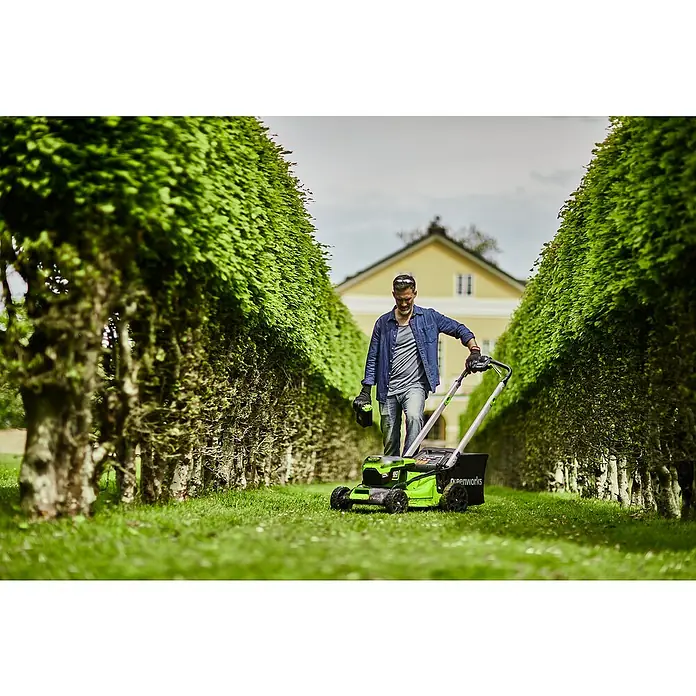Greenworks 60V Akkusystem Akku-Rasenmäher GD60LM51SP - 60 V, 1 Akku, 4 Ah, Schnittbreite: 51 cm - Ein Mann mäht den Rasen mit einem Greenworks Rasenmäher, umgeben von üppigem Grün.