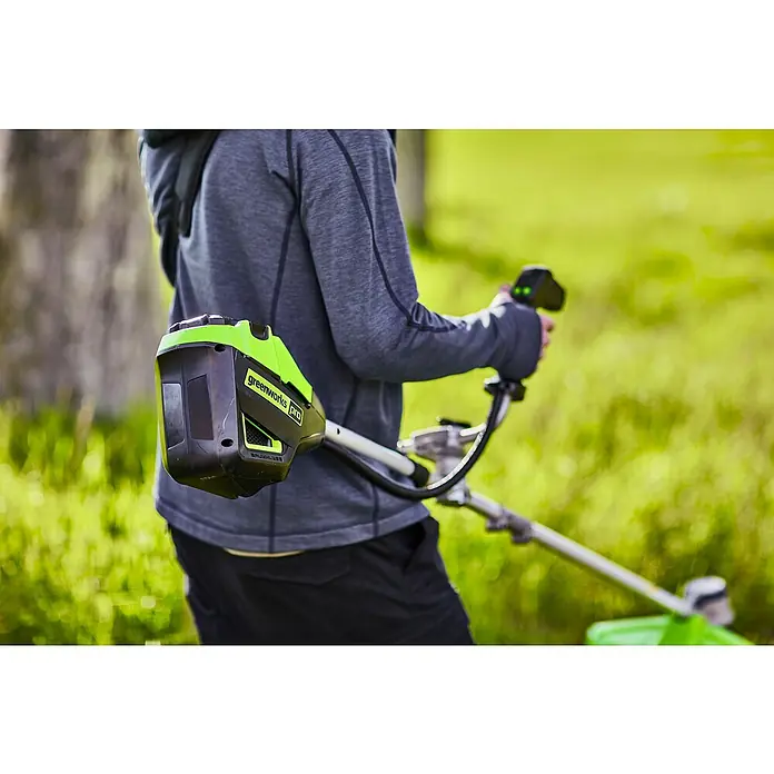 Greenworks 60V Akkusystem Akku-Rasentrimmer GD60BCB - 60 V, Li-Ionen, Ohne Akku, Schnittbreite Messer: 26 cm, Schnittbreite Faden: 40 cm - Aufsicht auf eine Person, die einen Greenworks Pro Rasentrimmer mit Akku auf einem Rasen hält. Das Gerät ist schwarz mit grünen Akzenten.