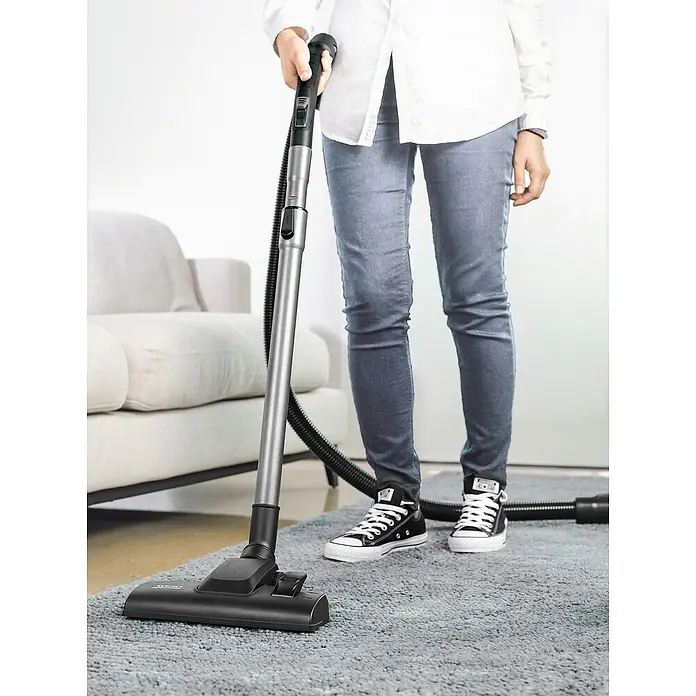 Kärcher Elektro-Staubsauger VC 2 - 700 W - Eine Person benutzt einen Kärcher Staubsauger zum Reinigen eines grauen Teppichs. Der Staubsauger hat ein schlankes Design mit einem silbernen Griff.