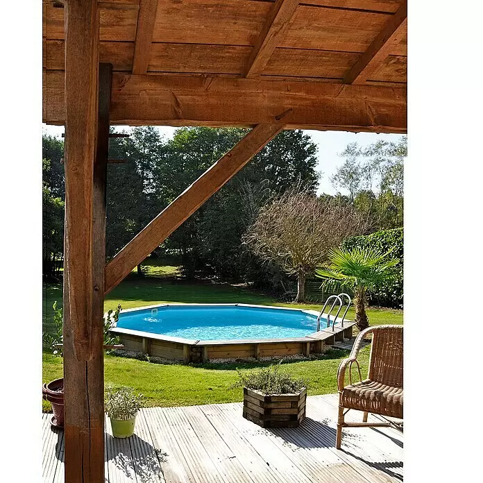Gre Holz-Pool Violette 2 - Ø x H: 500 x 127 cm, Braun, 15.500 l - Hölzernes Deck und Pergola mit Blick auf einen Garten mit blauem Aufstellpool, eine einladende Outdoor-Wohnfläche.