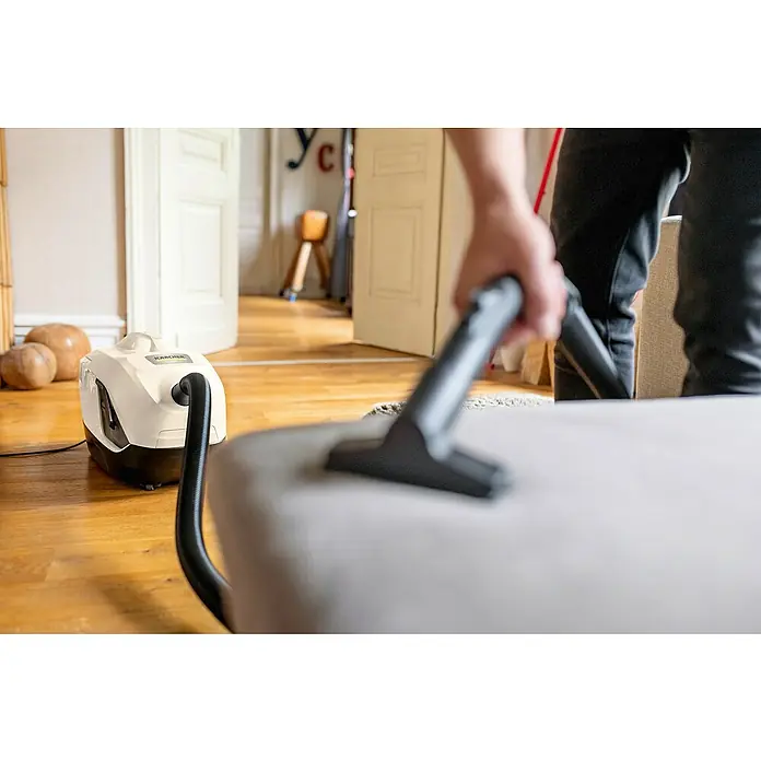 Kärcher Elektro-Staubsauger DS 6 - 650 W - Der Kärcher Waschsauger in Aktion, während er ein Möbelstück reinigt. Das Gerät steht auf einem Holzboden in einem hellen Raum.