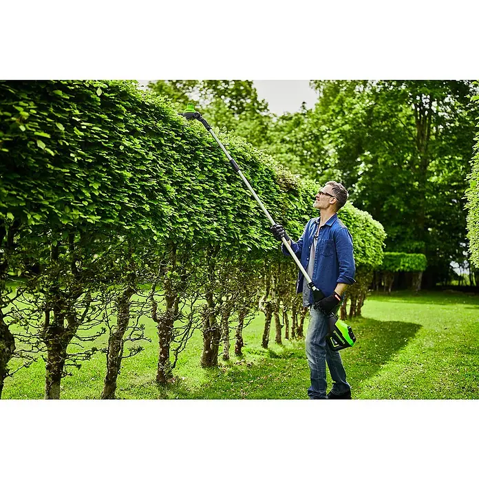 Greenworks 60V Akkusystem Teleskop-Heckenschere GD60PHT51 - 60 V, Li-Ionen, Ohne Akku, Schnittlänge: 51 cm - Ein Mann schneidet mit einer Greenworks Akku-Heckenschere eine Hecke im Garten. Die Heckenschere ist kabellos und hat einen Teleskopstiel für hohe Hecken.