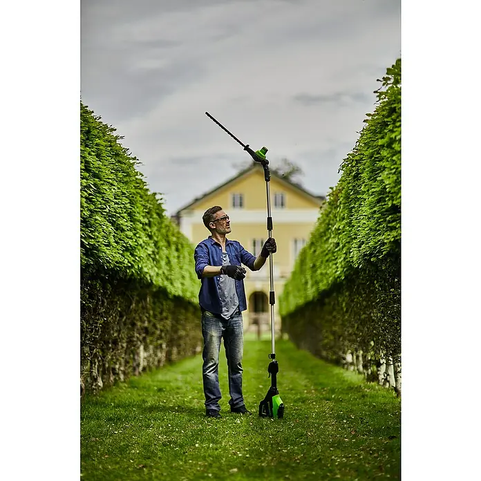 Greenworks 60V Akkusystem Teleskop-Heckenschere GD60PHT51 - 60 V, Li-Ionen, Ohne Akku, Schnittlänge: 51 cm - Ein Mann benutzt eine Greenworks-Akku-Heckenschere mit Teleskopstiel, um eine hohe Hecke zu schneiden.