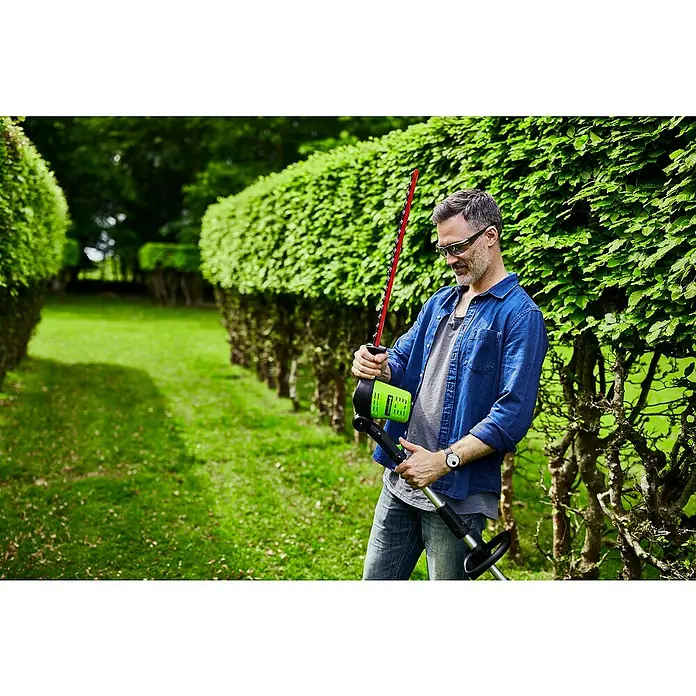Greenworks 60V Akkusystem Teleskop-Heckenschere GD60PHT51 - 60 V, Li-Ionen, Ohne Akku, Schnittlänge: 51 cm - Ein Mann im Garten mit einer grünen Heckenschere in der Hand, bereit für die Gartenarbeit.
