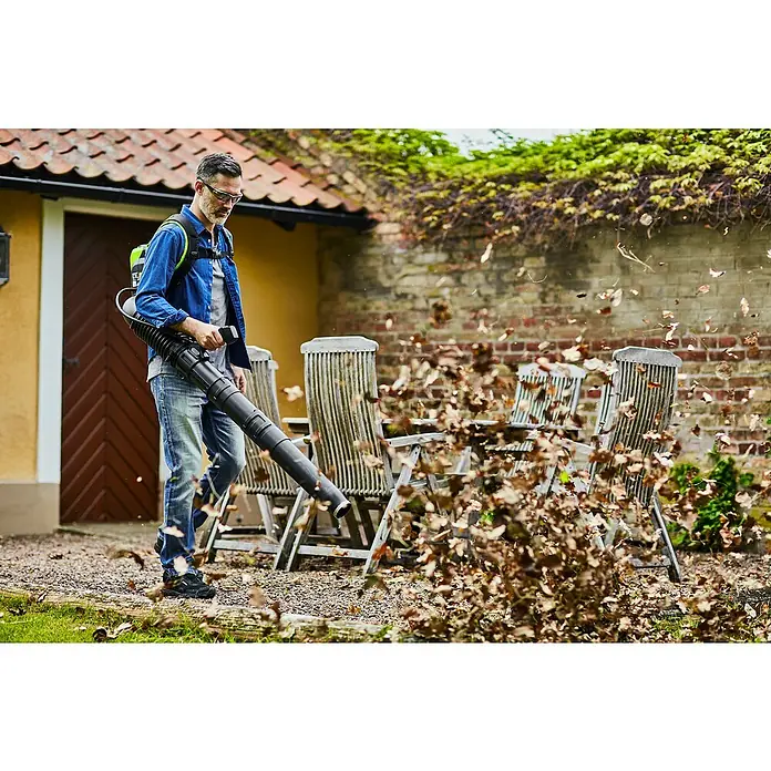 Greenworks 60V Akkusystem Akku-Laubbläser Rucksackbläser GD60BPB - Ohne Akku, Blasgeschwindigkeit: 257 km/h, Blasleistung: 540 m³/min - Ein Mann benutzt einen Laubbläser, um Blätter von einer Terrasse zu entfernen, wobei der Laubbläser im Fokus steht.
