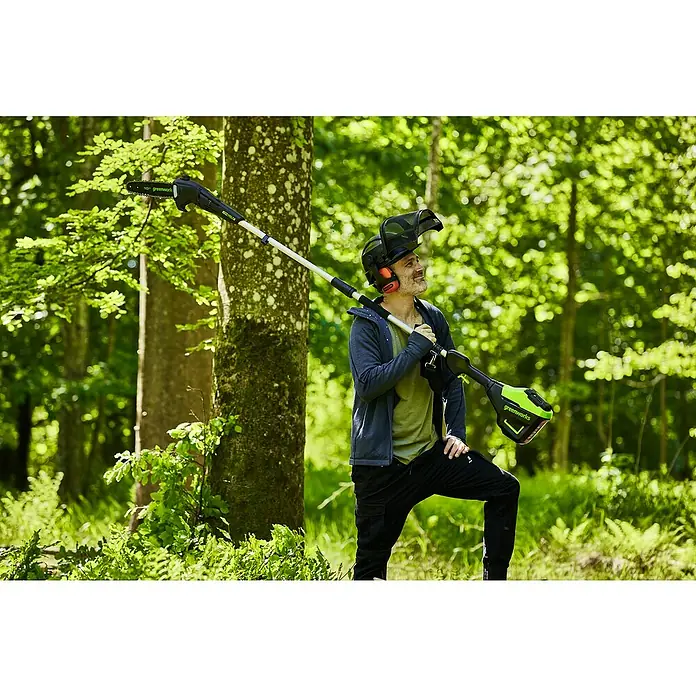 Greenworks 60V Akkusystem Akku-Hochentaster GD60PS25 - 60 V, Ohne Akku, Schwertlänge: 25 cm - Ein Mann mit einer Greenworks Hochentaster, der in einem üppigen, grünen Wald steht und Baumpflege betreibt.