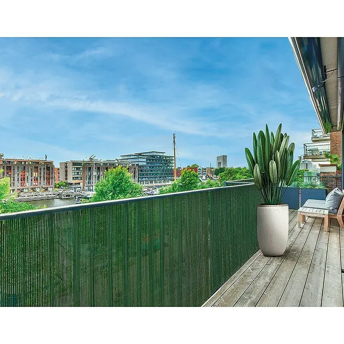 Nortene Ocultación de mimbre Fency Wick - L x Al: 3 x 1 m, Plástico, Verde - Pantalla de privacidad de caña verde en un balcón con vistas a un paisaje urbano, que combina privacidad y estética natural.