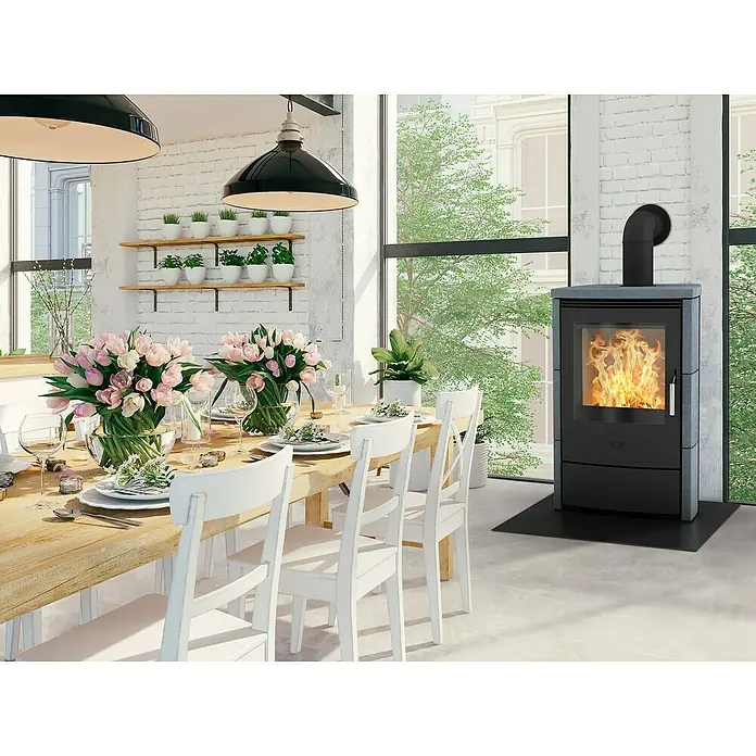 Fireplace Kaminofen Meltemi - 8,4 kW, Raumheizvermögen: 126 m³, Material Verkleidung: Speckstein, Schwarz - Ein moderner Kaminofen mit Flammen steht in einem hellen Raum und sorgt für Wärme und Atmosphäre.