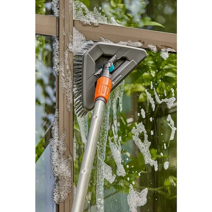 Gardena Gelenk-Schrubber Cleansystem - Abwinkelbares Gelenk - Bild einer Fensterreinigungsbürste von Gardena in Aktion, die an einem Fenster mit Seifenlauge verwendet wird.