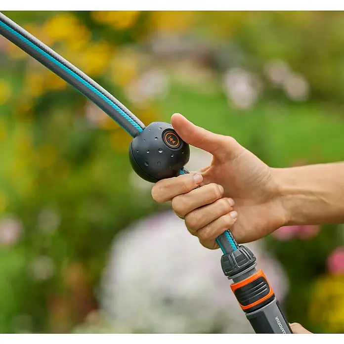 Gardena Power for All 18V Enrollador de manguera de batería Power-Roll XL - 18 V, Sin batería, Longitud del tubo: 35 m - Primer plano de una manguera de jardín GARDENA con un novedoso regulador sostenido en la mano, ideal para jardinería.