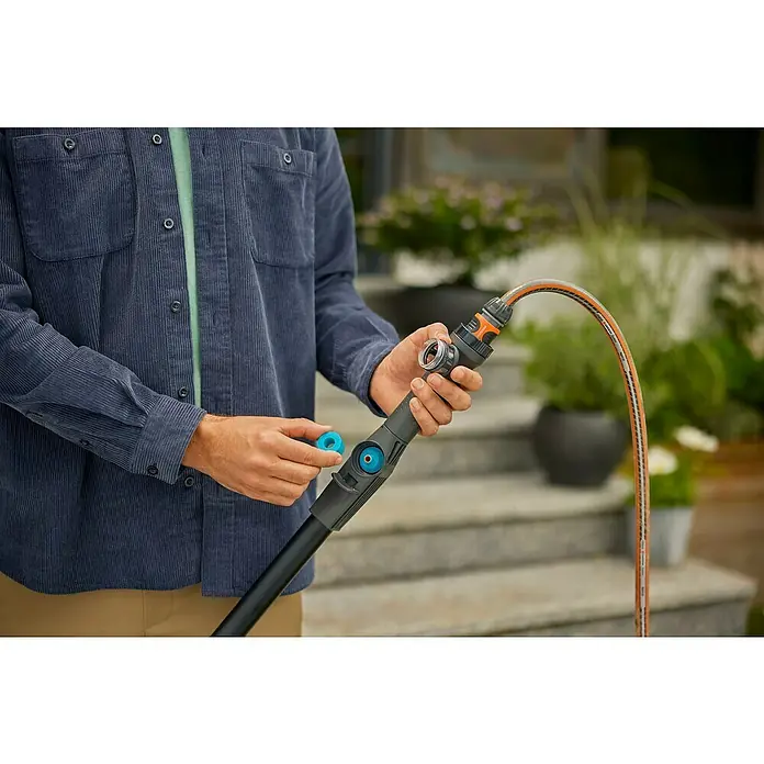 Gardena Cleansystem Teleskop-Wasserstiel Cleansystem - 155 cm - 260 cm, Aluminium - Nahaufnahme einer Person, die ein Gardena-Bewässerungssystem verbindet. Das Gerät ist schwarz mit blauen Akzenten.