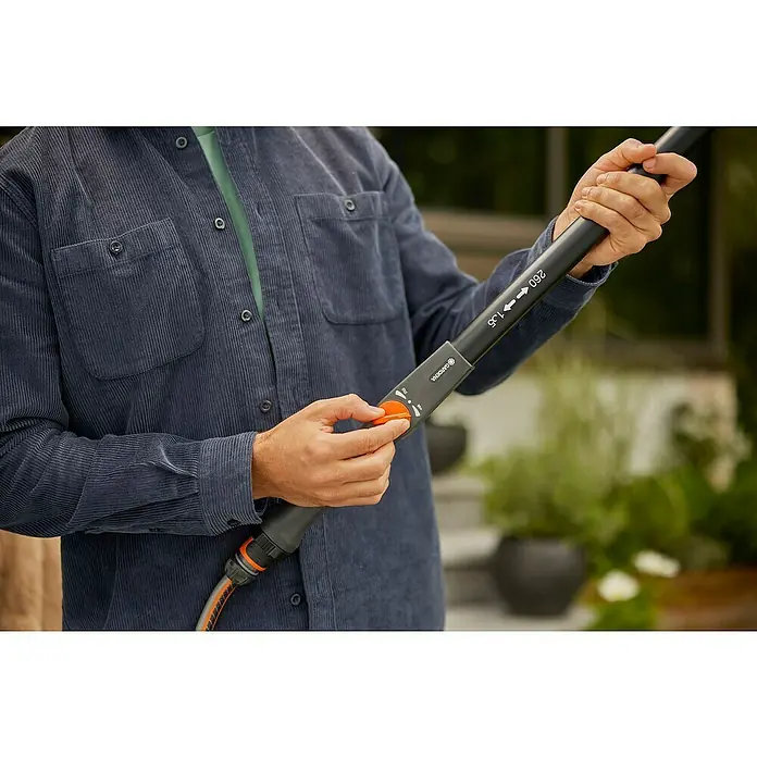 Gardena Cleansystem Teleskop-Wasserstiel Cleansystem - 155 cm - 260 cm, Aluminium - Ein Mann bedient eine Gardena Teleskop-Bürste mit Wasserdurchlauf zur Reinigung. Das Gerät ist grau und hat einen orangefarbenen Knopf.