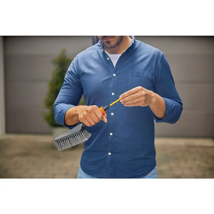 Gardena Waschbürsten-Set Cleansystem M Soft - Wasserführend - Mann montiert eine Terrassenbürste mit Wasseranschluss. Eine effiziente Reinigungslösung für den Außenbereich.