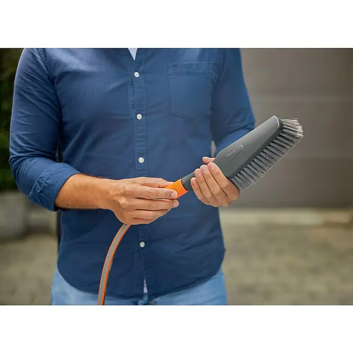 Gardena Waschbürsten-Set Cleansystem M Soft - Wasserführend - Mann hält eine GARDENA Waschbürste mit Wasseranschluss in den Händen, ideal zur Reinigung von Autos und Gartenmöbeln.