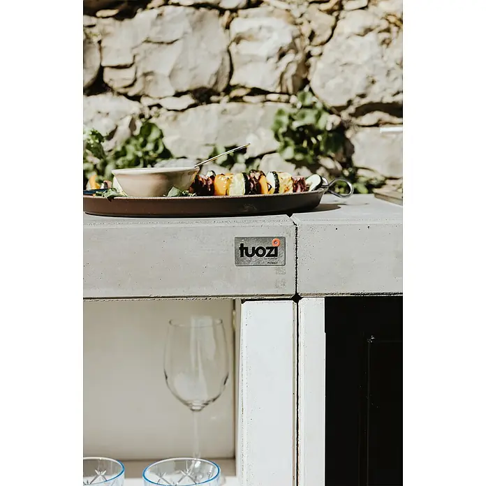 Tuozi Venit Outdoorküchen-Modul Seitenschrank - Weiß-Grau, B x T x H: 78 x 47 x 88 cm - Nahaufnahme eines Tellers mit köstlichen Gemüsespießen auf einer grauen Küchentheke mit "tuozi"-Logo und Gläsern.