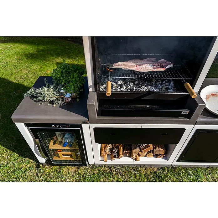 Tuozi Kitaway Schublade - Schwarz, Passend für: Tuozi Kitaway Grills & Grillküchen Module - Nahaufnahme eines modernen Grillbereichs im Freien mit Holzkohlegrill, Kühlbox und Holzaufbewahrung, ideal für entspannte Grillabende.