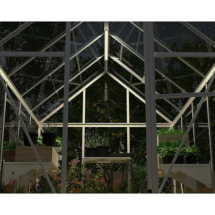 Palram – Canopia Lámpara fluorescente LED - 10 W, 1,8 x 67 x 0,7 cm - Vista detallada de un invernadero por la noche, con plantas en macetas y estanterías. La iluminación resalta la estructura delicada y las plantas.