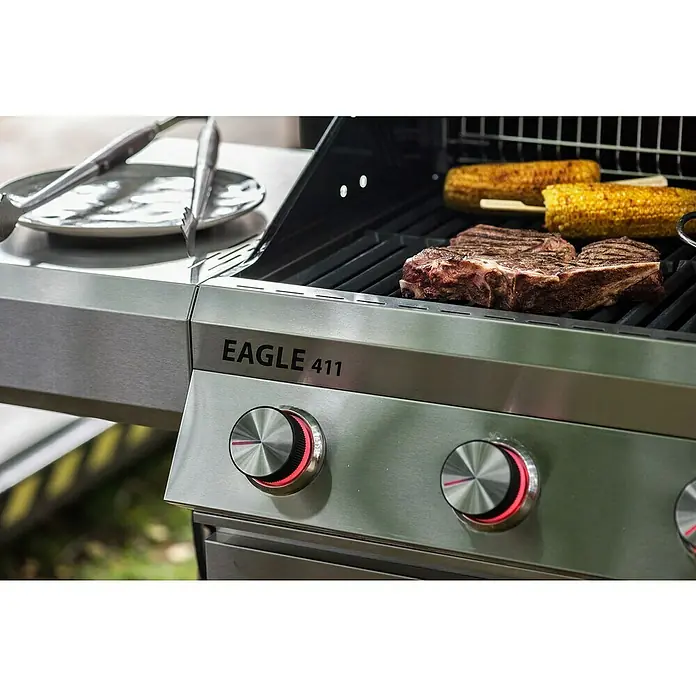 Grandstate Gasgrill Eagle 411 - Grillfläche (B x T): 71 x 45 cm, 14 kW, Anzahl Brenner: 4 Stk., Material Grillfläche: Gusseisen - Edelstahlgrill mit saftigen Steaks und Maiskolben. Die Bedienelemente leuchten rot, während die Zange auf einer Platte bereitliegt.