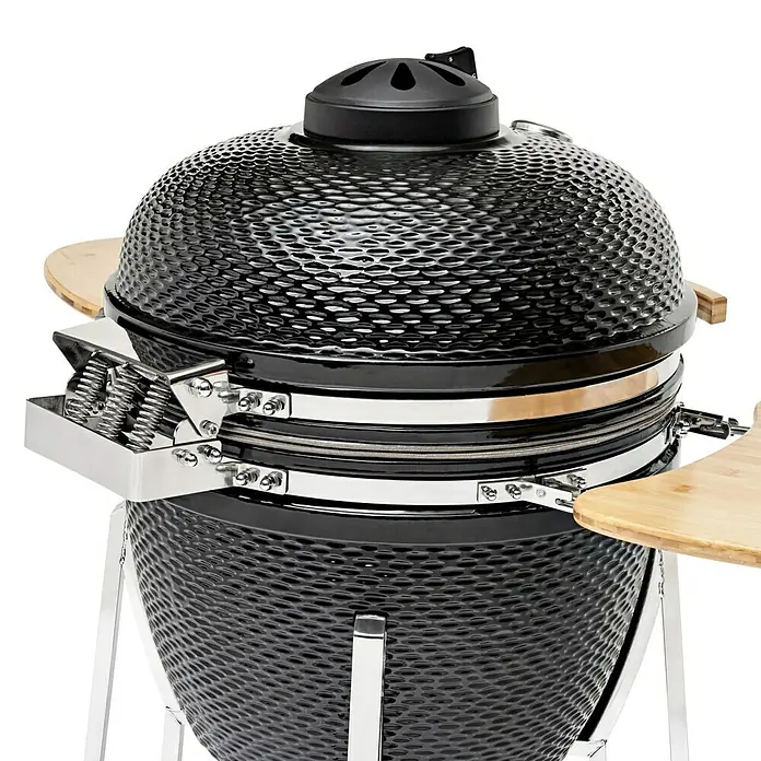 Flame Rock  Holzkohlegrill Kamado 24 Pro - Durchmesser Grillfläche: 52 cm, Schwarz - Nahaufnahme eines schwarzen Keramikgrills mit Holzablagen. Das Grillgerät steht auf einem silbernen Gestell und hat ein genopptes Äußeres.