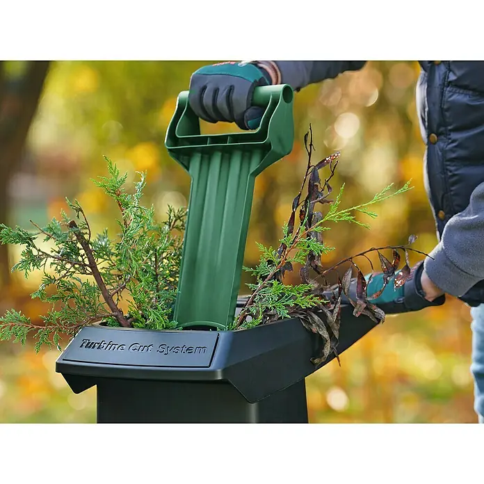Bosch Elektro-Häcksler AXT 25 TC - Max. Aststärke: 4,5 cm, 2.500 W - Eine Person benutzt einen Gartenhäcksler mit "Turbine Cut System", um Äste und Pflanzenreste zu zerkleinern.