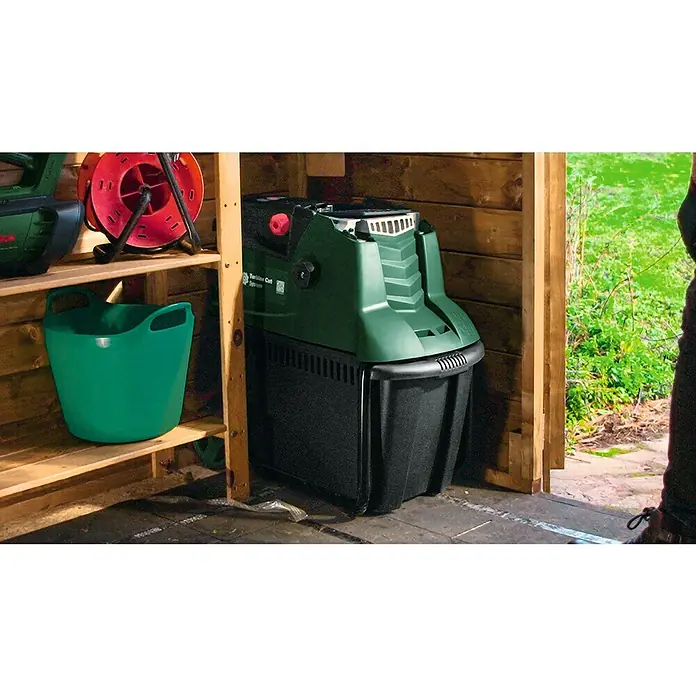 Bosch Elektro-Häcksler AXT 25 TC - Max. Aststärke: 4,5 cm, 2.500 W - Gartengeräte im Schuppen, darunter ein grüner Häcksler, ein rotes Kabelaufroller und ein grüner Eimer auf einem Regal.