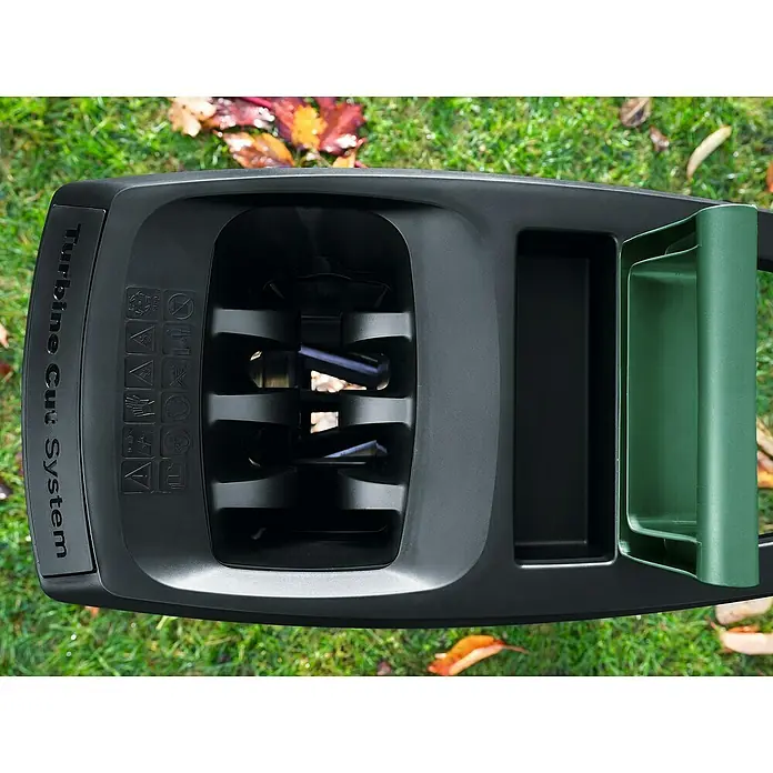 Bosch Elektro-Häcksler AXT 25 TC - Max. Aststärke: 4,5 cm, 2.500 W - Detailansicht eines Gartenhäckslers mit Turbine Cut System, der auf Rasen steht. Fokus auf die Schneidvorrichtung und Sicherheitsaufkleber.