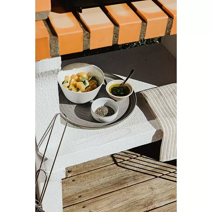 Movelar New Iberia Holzkohlegrill - Grillfläche (B x T): 56 x 35 cm, Grau, B x T x H: 95 x 47 x 190 cm - Orangen-Avocado-Salat, grüne Soße und Kräuter auf grauem Tablett, mit Zange und gestreiftem Tuch im sonnigen Außenbereich.