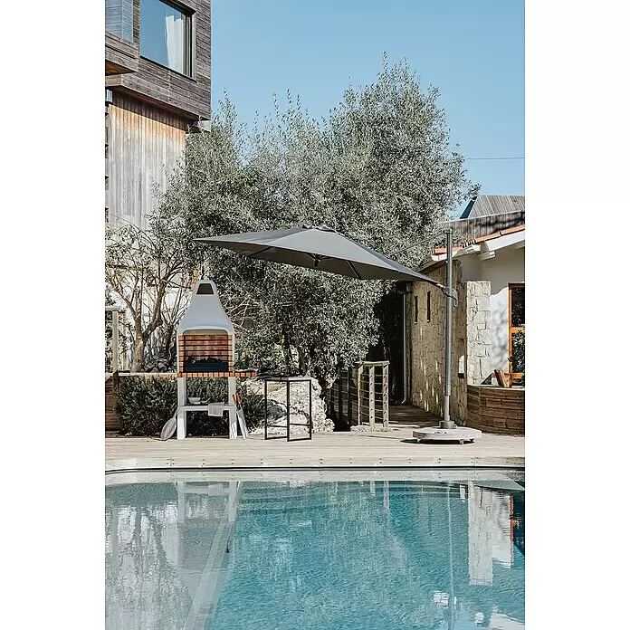 Movelar New Iberia Holzkohlegrill - Grillfläche (B x T): 56 x 35 cm, Grau, B x T x H: 95 x 47 x 190 cm - Großer dunkelgrauer Ampelschirm spendet Schatten auf einer Holzterrasse neben Pool und Grill.
