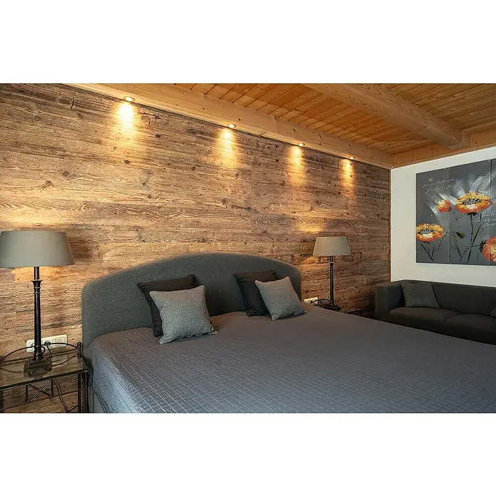 Egger Wandpaneel DecoWall - Namur Fichte Natur, 125 cm x 66 cm x 12 mm - Schlafzimmer mit Holzwand, graublauen Bettwäsche und Nachttischlampen, das eine ruhige und natürliche Atmosphäre schafft.