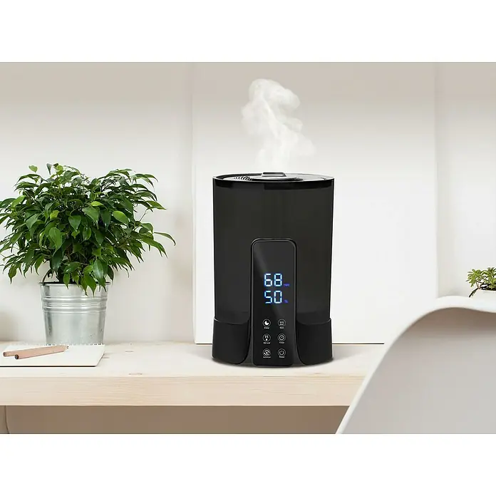 Purline Humidificador Hydro 18 - 22 x 22 x 32 cm, Negro - Humidificador sobre una mesa con plantas. El dispositivo muestra la temperatura y la humedad y emite vapor.