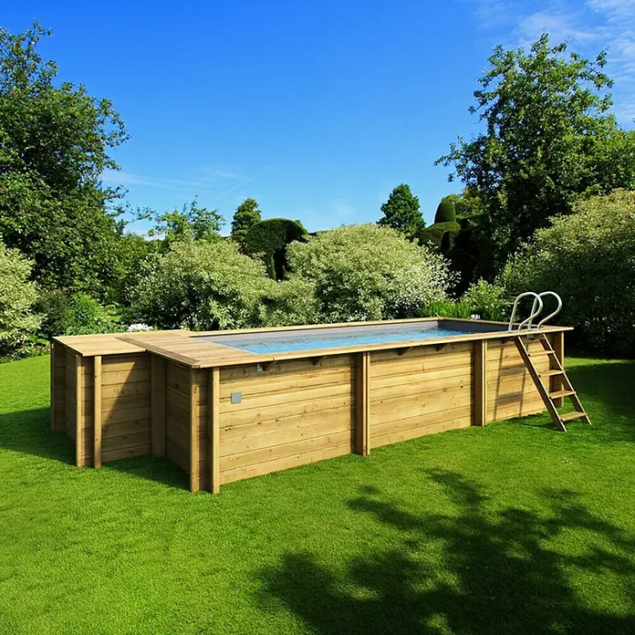 myPool Holz-Pool Urban - 486 x 401 x 133 cm, 11.000 l, Braun, Grau - Ein rechteckiger Holzpool mit einer Leiter steht auf einem grünen Rasen vor üppigen Büschen und Bäumen unter einem blauen Himmel.